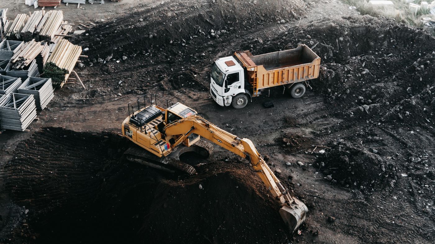 Locação de equipamentos: Escavadeira e caminhão basculante em operação industrial
